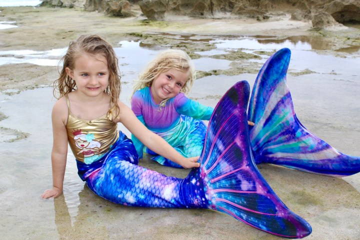 a little girl sitting next to a body of water