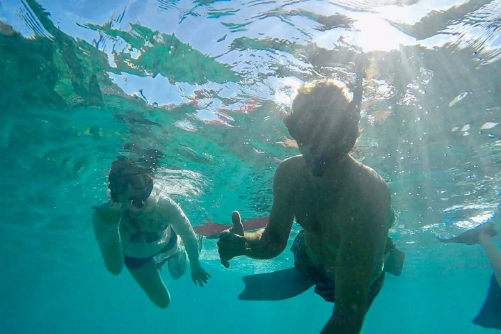 Two people snorkeling underwater, one giving a thumbs-up.